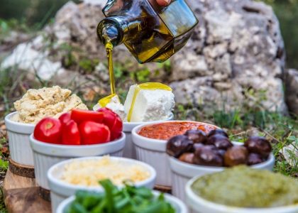 Outdoor picnic with various Mediterranean spreads, herbs, and olive oil drizzle.