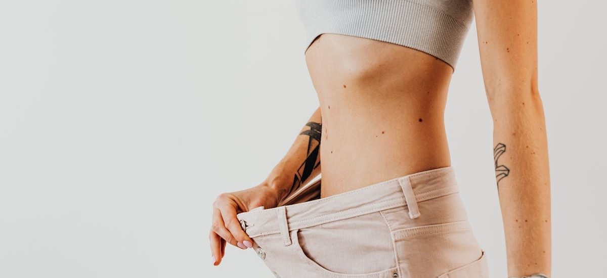 Close-up of a woman in oversized jeans symbolizing weight loss in a studio setting.