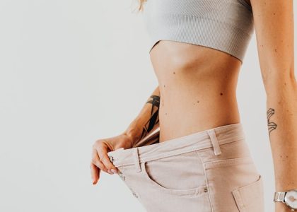 Close-up of a woman in oversized jeans symbolizing weight loss in a studio setting.